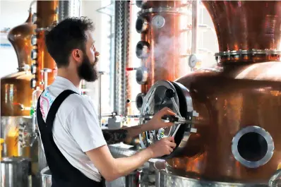  ?? East London Liquor Company via AP ?? ■ Distiller Sam Garbutt checks distillery controls in 2018 in the Dewer’s Distillery