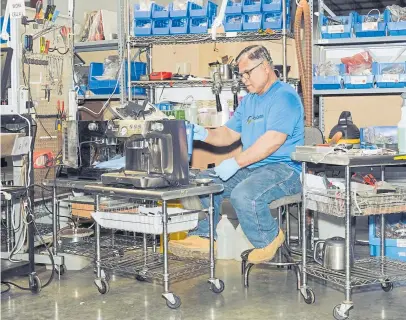  ??  ?? An employee works on a coffee maker during the remanufact­uring process at CoreCentri­c Solutions in Carol Stream, Ill. Products as large as a medical imaging machine can now be upgraded.