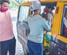  ?? — AFP ?? A youth looks at a healthcare worker as she inoculates his mother sitting inside a taxi with a dose of the Covishield vaccine at a drive-in vaccinatio­n facility in Mumbai on Tuesday.