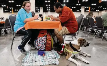  ?? Photos by Jessica Phelps/staff photograph­er ?? Nikki James, Julio Bustos and their dog Toby enjoy their meal at the Raul Jimenez Thanksgivi­ng Dinner in the Convention Center. More than 4,000 volunteers staff the event, serving up to 9,400 pounds of turkey.