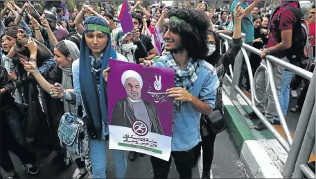  ?? Picture: AFP ?? NEW LEADER: Supporters of newly re-elected Iranian President Hassan Rouhani carry a placard bearing a portrait of him during a rally to celebrate his victory in Tehran on Saturday