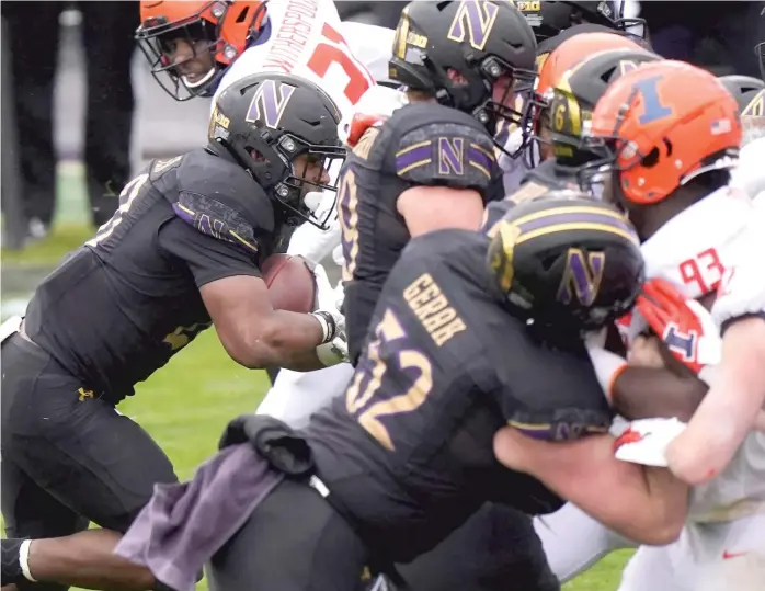  ?? AP ?? Northweste­rn running back Cam Porter ( left) squeezes past the Illinois defense to score a touchdown in the second quarter. Porter, who had a career- high 142 yards on 24 carries, also rushed for a touchdown in the third quarter.