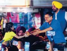  ?? ANI ?? ■
■ Arvind Kejriwal receives a piggy bank from a young girl as he holds a roadshow, in New Delhi, on Saturday.