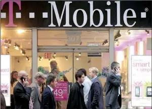  ?? Bloomberg NEWS/STEPHEN YANG ?? People pass a T-mobile USA Inc. store in New York in November. T-mobile on Tuesday said that Nokia Siemens Networks and LM Ericsson AB will supply the network equipment for its new $4 billion wireless broadband network.