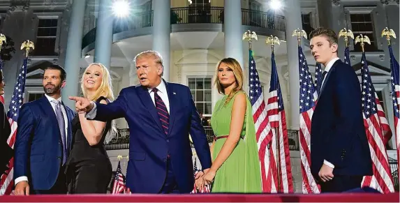  ?? FOTO ČTK/AP ?? Show v režii Trumpových. Rodina amerického prezidenta pózuje po nominačním projevu před Bílým domem a čeká na zahájení slavnostní­ho ohňostroje. Na snímku stojí vlevo nejstarší syn prezidenta Donald Trump mladší vedle své nevlastní sestry Tiffany. Uprostřed prezident Donald Trump drží za ruku svou manželku Melanii a vpravo je jejich čtrnáctile­tý syn Barron.