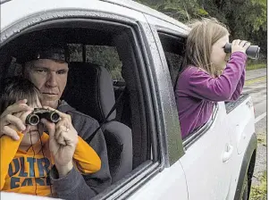  ?? Arkansas Democrat-Gazette/BILL BOWDEN ?? Blake Bowers of Conway helps his son Jordan, 4, adjust his binoculars Saturday while Bella Bowers, 5, already has the Boxley Valley elk in sight from the back seat.