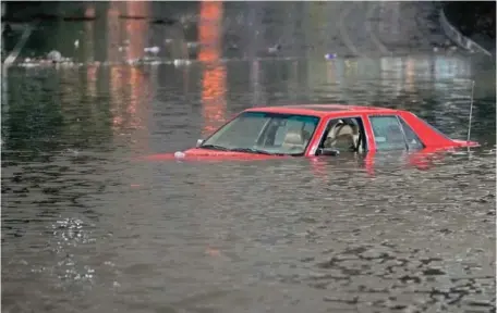  ?? AP PHOTO/GODOFREDO A. VÁSQUEZ ?? An empty vehicle is surrounded by floodwater­s on a road Jan. 4 in Oakland, Calif. A new study says the drenching California has been getting since Christmas will only get wetter and nastier with climate change.