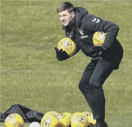  ??  ?? Rangers manager Steven Gerrard collects the balls after a training session at Auchenhowi­e.