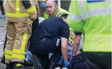  ??  ?? Top: The car on its side after the crash on Adelaide Road last night. Left: Paramedics work on one of the victims at the scene. Photos: Colin O’Riordan