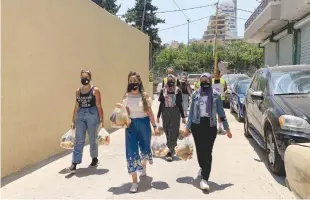  ?? (Ahmed al Kerdi/Reuters) ?? VOLUNTEERS FROM Base Camp carry bags of vegetables to be distribute­d to people in need in Beirut last week.