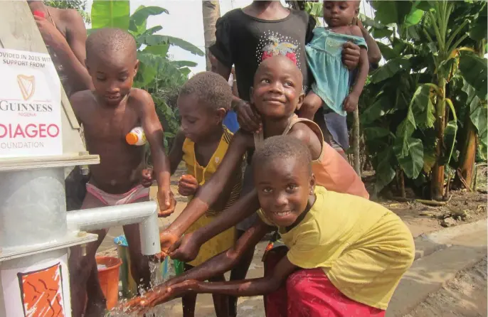  ??  ?? Children drinking water from one of the newly-constructe­d boreholes donated by Guinness Nigeria in the beneficiar­y communitie­s