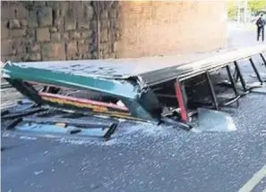  ??  ?? The roof of the double-decker bus lies underneath the bridge after the crash