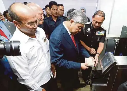 ?? [FOTO MUHD ZAABA ZAKERIA/BH] ?? Ahmad Zahid mencuba mesin autogate dan pengimbas wajah yang baharu sambil diperhatik­an Mustafar pada majlis perasmian kilang Datasonic di Petaling Jaya, semalam.