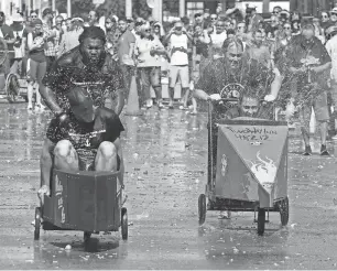  ?? KIRTHMON F. DOZIER/DETROIT FREE PRESS ?? During the annual Hamtramck yacht races, teams of patrons from local bars race down Joseph Campau in carts shaped like boats while being pelted with water balloons by onlookers. The event is a Labor Day tradition in the city.