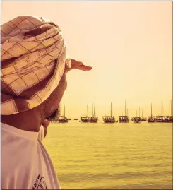  ??  ?? A Marine Heritage Committee member watches approachin­g sailboats at the shore of
Kuwait Sea Club. (Ahmad Darwish — KUNA)