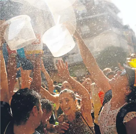  ??  ?? Revellers cover each other in water during the annual water fight at the Vallecas neighborho­od in Madrid.