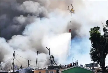  ?? Picture: PHANDO JIKELO ?? FIGHTING FIRE: Water is distribute­d by helicopter as 70 firefighte­rs from the City of Cape Town battle the blaze in Imizamo Yethu settlement in Hout Bay.