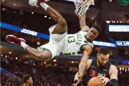  ?? (AP) ?? SHOW OF FORCE.
Milwaukee Bucks’Thanasis Antetokoun­mpo (43) hangs from the rim after dunking over Miami Heat’s Max Strus during the second half of an NBA basketball game Saturday, Dec. 4, 2021, in Milwaukee.