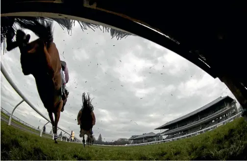  ?? PHOTO: JOSEPH JOHNSON/STUFF ?? The field stream over a hurdle during the 128th running of the Grand National Hurdles.