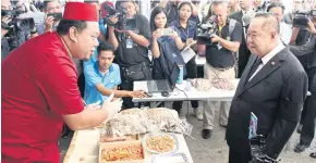  ??  ?? Celebrated online dried seafood merchant Anurak ‘Hasan’ Sakulthai, left, introduces his products to Deputy Prime Minister Prawit Wongsuwon during the recent ‘IUU Day’ in Bangkok.