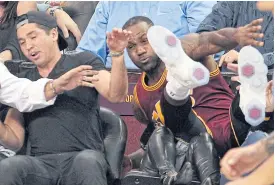  ??  ?? The Cavaliers’ LeBron James crashes into Ellie Day, wife of PGA Tour golf player Jason Day.
