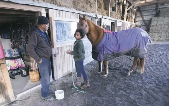  ??  ?? Kutztown farmer Ray Chavous is shown at his horse barn with granddaugh­ter Dasha Toure earlier this month.