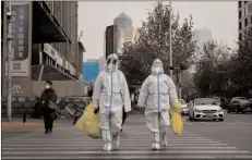  ?? -AFP ?? BEIJING
Pandemic prevention workers in protective suits cross a street as coronaviru­s disease (COVID-19) outbreaks continue in Beijing, China.