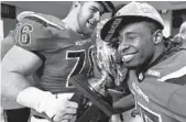  ?? MICHAEL NOBLE JR./AP ?? Western Kentucky offensive lineman Forrest Lamp, at left, and wide receiver Nicholas Norris embrace the Conference USA championsh­ip trophy in the locker room.