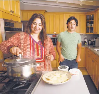  ?? Liz Hafalia / The Chronicle ?? Sowmya Rangaswamy makes lunch with her teenage son, Ayush Thirumala, in the new home they bought in Mountain View through Reali, which is using technology to lower costs.
