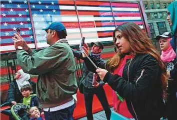  ?? AFP ?? A group of Syrian and Iraqi refugee families take selfies in Times Square during a tour of Manhattan on Friday.