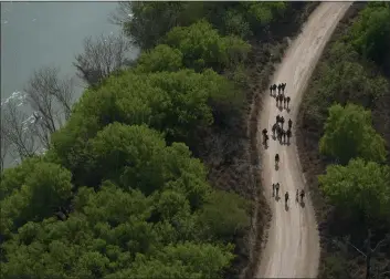  ?? PHOTOS BY JULIO CORTEZ — THE ASSOCIATED PRESS ?? Migrants walk on a dirt road after crossing the U.S.-Mexico border in Mission, Texas, on Tuesday.