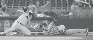  ?? WILFREDO LEE/| AP ?? Marlins third baseman Isan Diaz is unable to tag the Mets’ Javier Baez as Baez takes third on a wild pitch by Jesus Luzardo in the first inning Thursday in Miami.