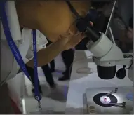  ?? (AP/Mark Schiefelbe­in) ?? A visitor uses a microscope to look at a microchip on display by the state-controlled Tsinghua Unigroup project at the 21st China Beijing Internatio­nal High-tech Expo in Beijing in 2018.