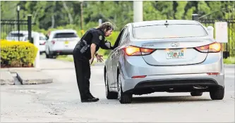  ?? JACOB LANGSTON TNS ?? A police officer speaks with a driver at the Westbrook Apartments in Orlando on Tuesday. Four young children were discovered dead at an apartment complex late Monday, following a standoff.