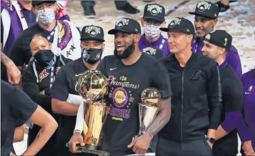  ??  ?? LeBron James posa con el trofeo Larry O’Brien (el cuarto que consigue) y el Premio Bill Rusell (también suma cuatro), al MVP de la final de la NBA.