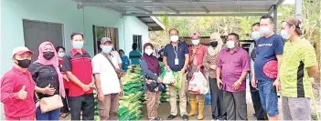  ??  ?? Ruddy (sixth left) handing over food baskets to villagers in Kg Mempakad Darat.
