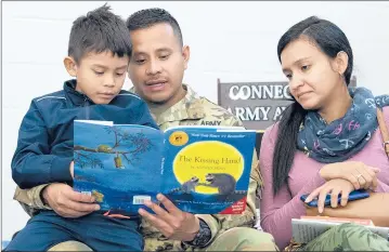  ?? PATRICK RAYCRAFT | PRAYCRAFT@COURANT.COM ?? CONNECTICU­T National Guard staff sergeant and tech engineer Jose Osorio, 36, reads with his son, Julian Osorio, 7, and wife, Johana, before his battalion heads out for a yearlong deployment to Afghanista­n.