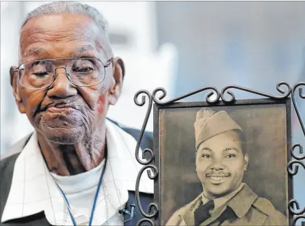  ?? Gerald Herbert
The Associated Press ?? World War II veteran Lawrence Brooks holds a photo of him taken in 1943, as he celebrates his 110th birthday in New Orleans in 2019. Brooks, who is now 112 years old, is the oldest living U.S. veteran. He was drafted to serve during WWII and assigned to the mostly-black 91st Engineer General Service Regiment.