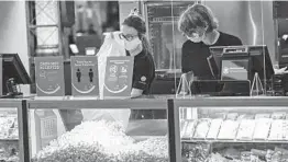  ?? KEITH SRAKOCIC/AP ?? AMC Theatres workers in western Pennsylvan­ia stock bins with popcorn Thursday as the movie venue reopened for the first time since the start of the coronaviru­s pandemic.