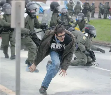  ?? PHIL CARPENTER THE GAZETTE ?? Protester runs from SQ riot police Friday during demonstrat­ions outside the Quebec Liberal Party’s policy meeting in Victoriavi­lle.