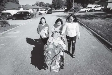  ?? EMILY MICHOT emichot@miamiheral­d.com ?? Justin is pushed around the block by his mother, center, in their Jacksonvil­le neighborho­od, accompanie­d by Jessica and Jennifer. The sisters say the family's struggles were no secret to NICA.