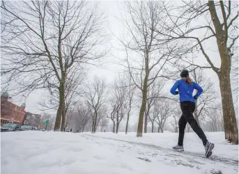  ?? DARIO AYALA/MONTREAL GAZETTE ?? A woman runs at Jeanne-Mance park during a moderate snow fall in Montreal.