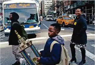  ??  ?? Tani, as he’s known, carrying his chess trophy home from school, accompanie­d by his mother and brother.