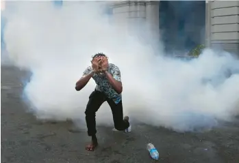  ?? ERANGA JAYAWARDEN­A/AP ?? A man runs from tear gas fired by police to quell anti-government protesters Thursday in Colombo, Sri Lanka. Also Thursday, Basil Rajapaska, the brother of the country’s president and a former finance minister, said he resigned from Parliament amid mounting criticism of his handling of an economic crisis that’s nearly bankrupted the island nation.