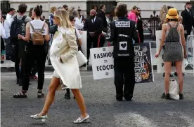  ??  ?? A show-goer walks past Extinction Rebellion protesters as they demonstrat­e against London fashion week. Photograph: Peter Nicholls/Reuters