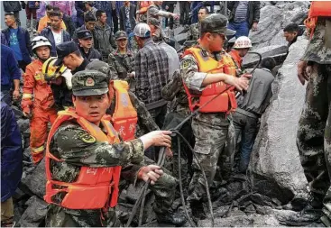  ?? Chinatopix via Associated Press ?? Emergency personnel work at the site of a massive landslide Saturday in Xinmo village in Maoxian County in southweste­rn China’s Sichuan Province. Officials estimated that 118 people are still missing.