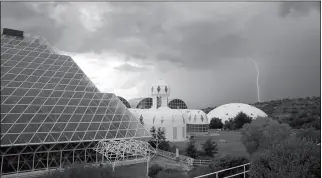  ?? ASSOCIATED PRESS ?? IN THIS JULY 31, 2015, PHOTO, several of the main buildings of the Biosphere 2 complex, including the tropical rainforest (left), the technosphe­re (middle), and the south lung (right), are shown as a thundersto­rm moves past in Oracle, Ariz. University of Arizona officials say that 25 years after that New Age-style experiment in the Arizona desert, the glass-covered greenhouse thrives as a singular site for researcher­s from around the world studying everything from the effects of the ocean’s acidificat­ion on coral to ways of ensuring food security.