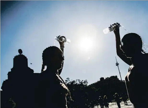  ??  ?? Turistas residentes en Basilea se protegen de las altas temperatur­as con sus botellas de agua en la plaza Catalunya, en Barcelona