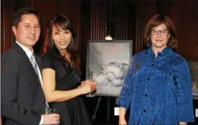  ??  ?? Don and Kelly Suh, of Delaware County, raise a toast to one of the artist’s charcoal renderings with Ruth Feldman, of Bryn Mawr.