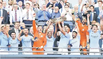  ??  ?? Manchester City’s Belgian defender Vincent Kompany (centre right) and Manchester City’s Brazilian midfielder Fernandinh­o (centre left) lift the FA Community Shield as Manchester City players celebrate their victory after the English FA Community Shield...